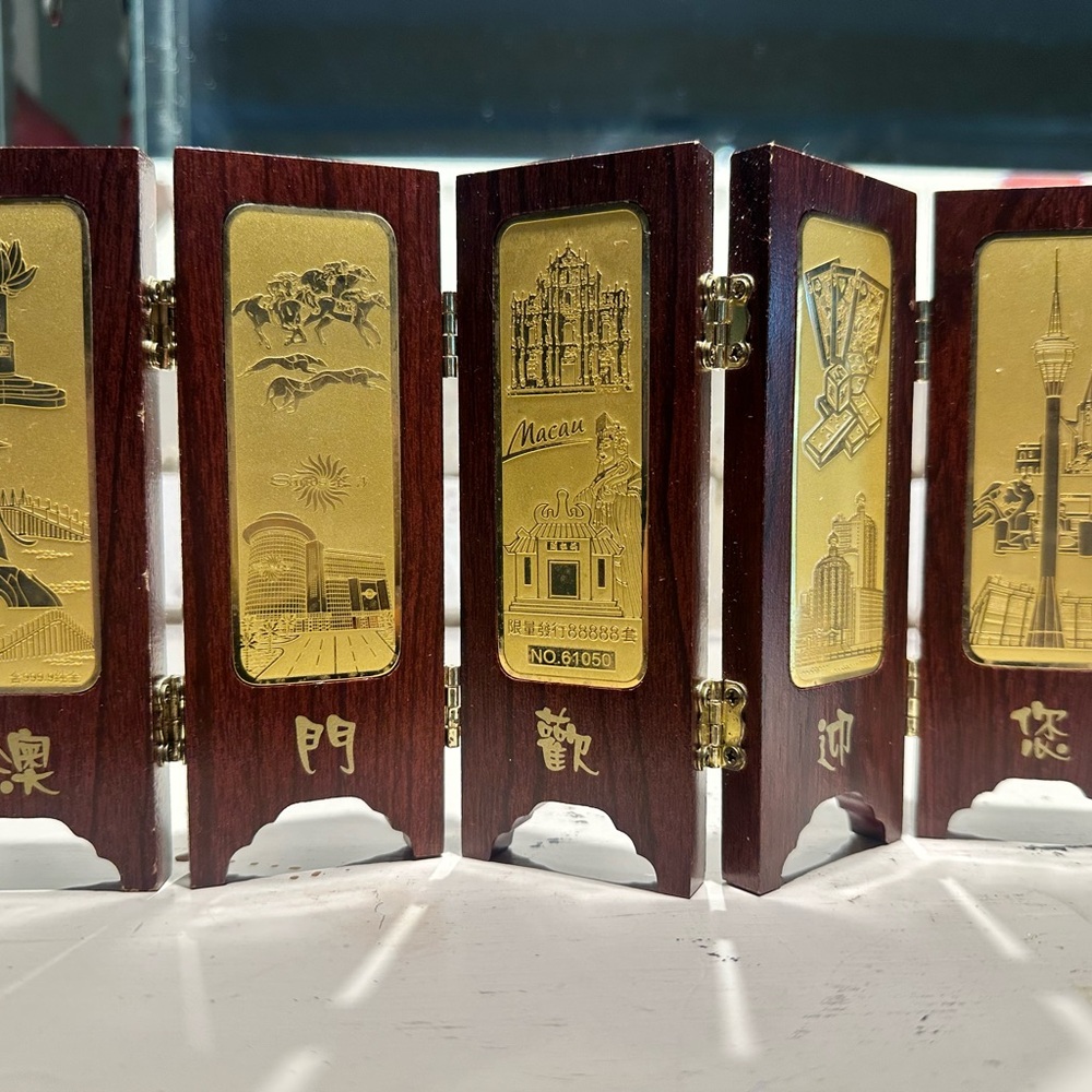 Decorative Macau commemorative folding screen with gold-toned plaques.
